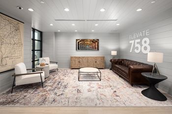 a living room with a brown leather couch and two white chairs